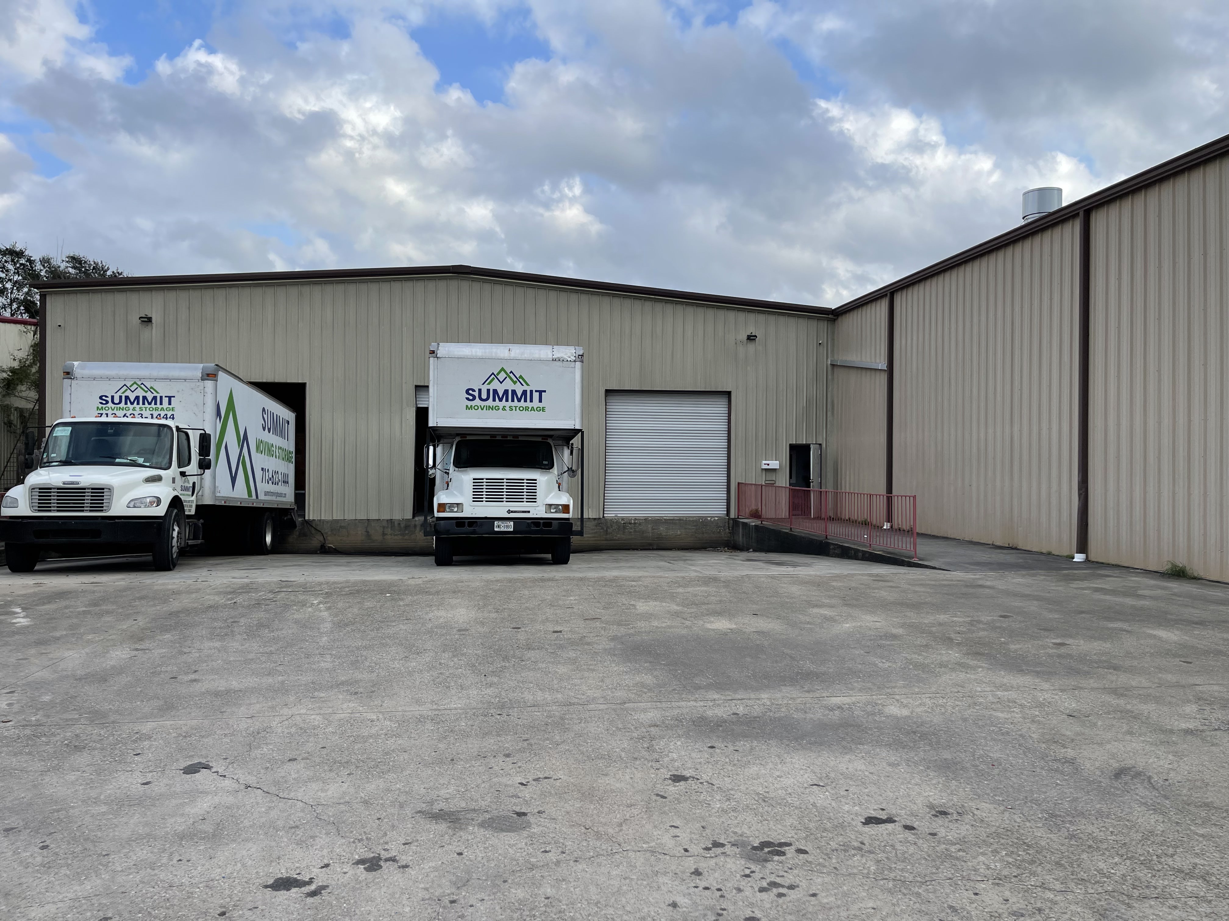 Two Summit Moving & Storage box trucks parked at the loading bays of the company warehouse