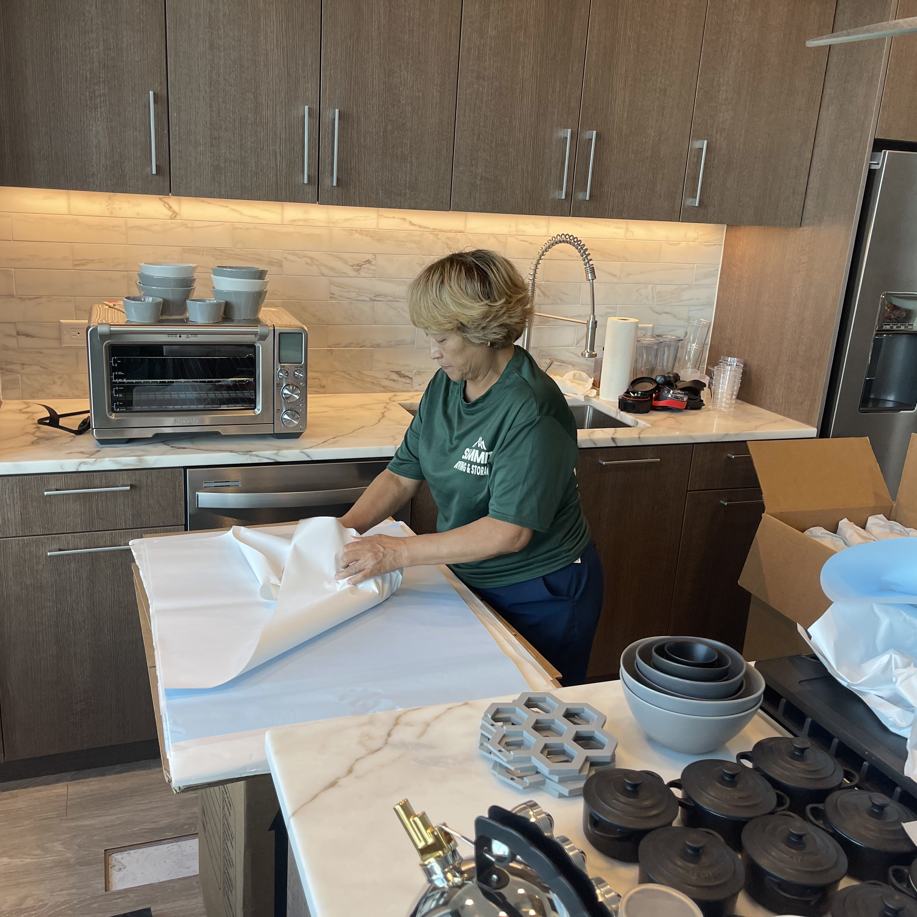 A Summit crew member packing fragile dishes into a cardboard box in a high-rise apartment overlooking River Oaks