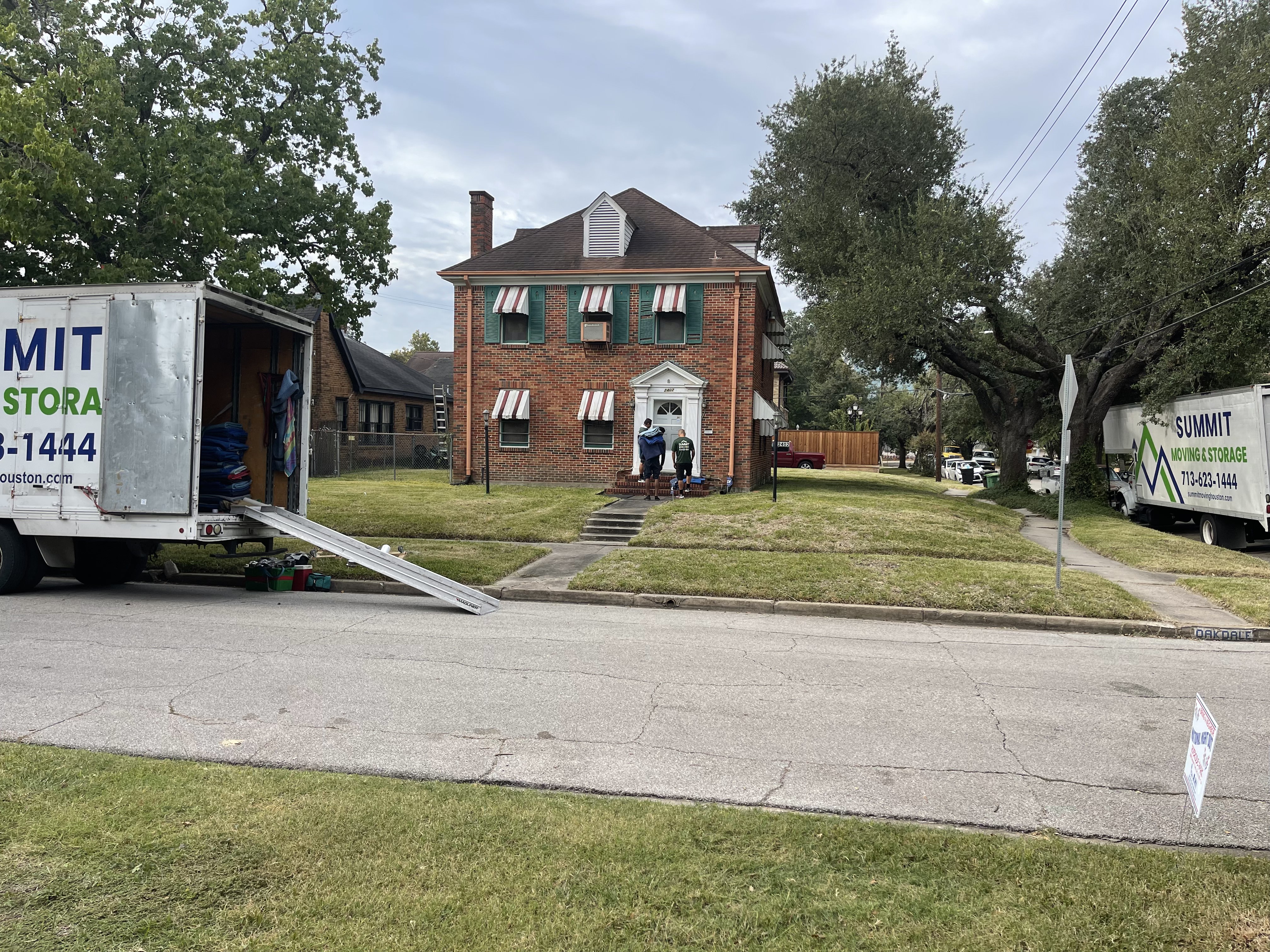 A Summit truck with its ramp down outside a two-storey brick house while the crew works at the front door