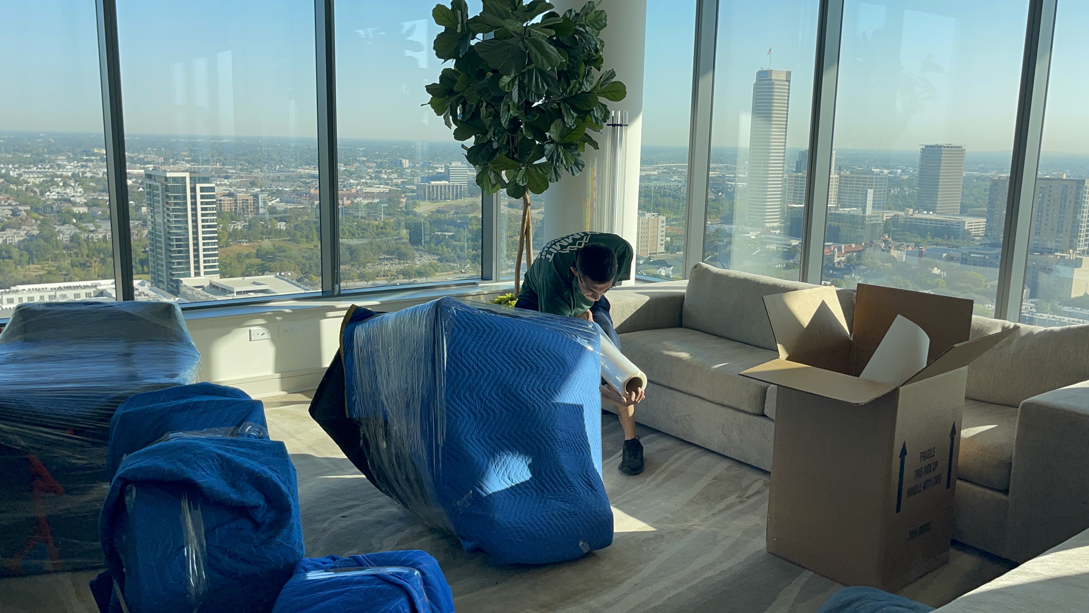 A Summit crew member wrapping an armchair in protective blankets in a high-rise apartment overlooking Houston